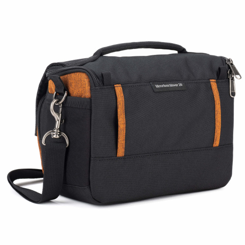 Schräge Rückansicht einer orange-schwarzen Think Tank Mirrorless Mover 20 V2 Kameratasche in der Farbe Campfire Orange vor weißem Hintergrund mit gepolstertem Tragegriff, montiertem Schultergurt und einer breiten Gürteldurchführung auf der Rückseite.