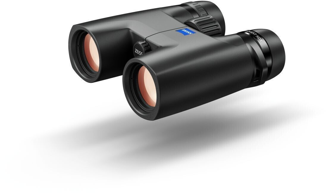 Ein kompaktes, schwarzes ZEISS Conquest HDX Fernglas in einer perspektivischen Ansicht von vorne und oben, freigestellt auf weißem Hintergrund mit einem weichen Schattenwurf. Die beiden Frontlinsen zeigen eine rötlich-orange Antireflexbeschichtung. Auf de