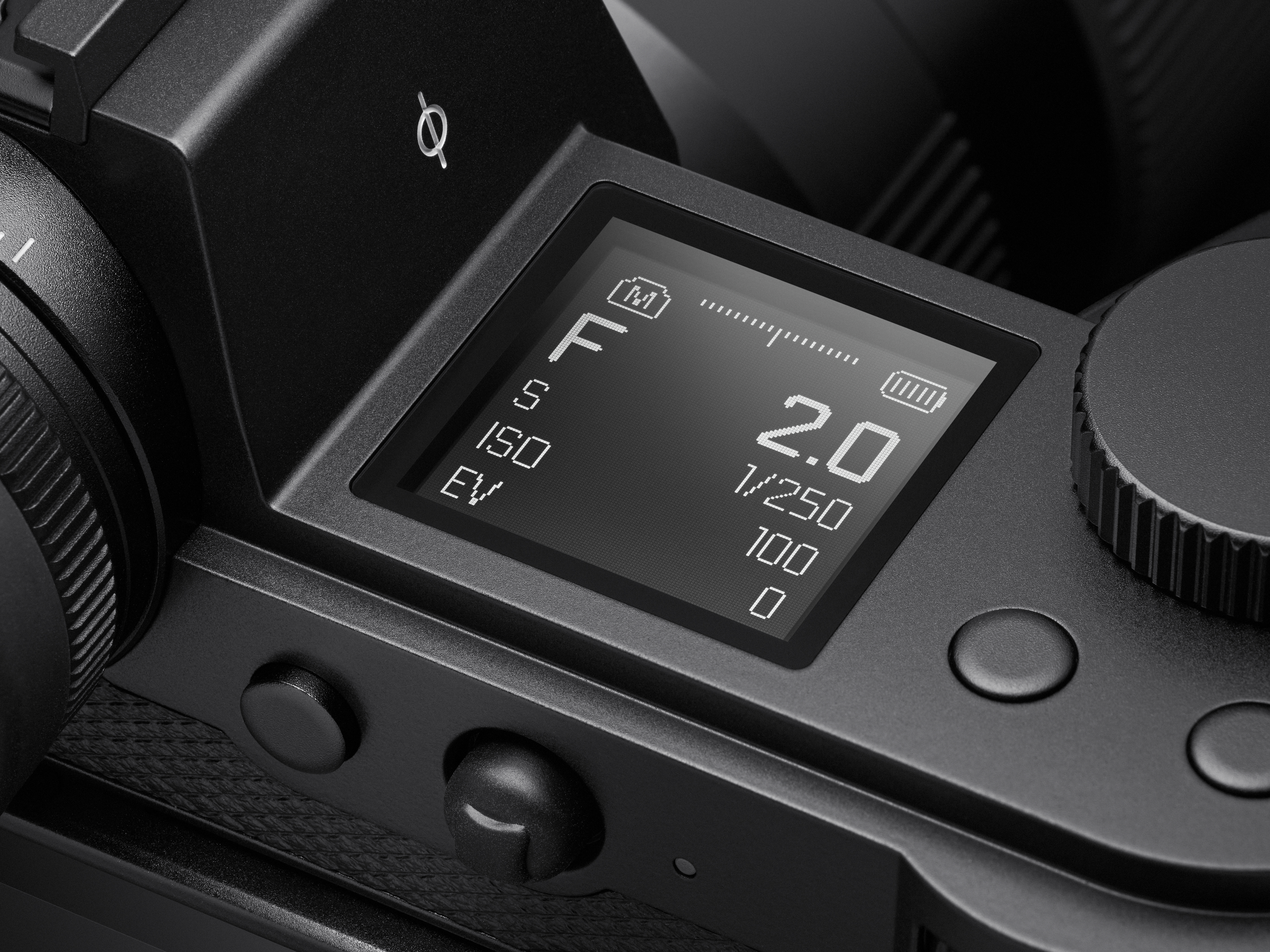 Eine detailreiche Nahaufnahme des beleuchteten E-Ink-Schulterdisplays einer Leica SL3 Systemkamera in der Draufsicht, das aktuelle Belichtungsparameter wie Blende f/2.0, Verschlusszeit 1/250s und ISO 100 im manuellen Belichtungsmodus (M) kontrastreich anz