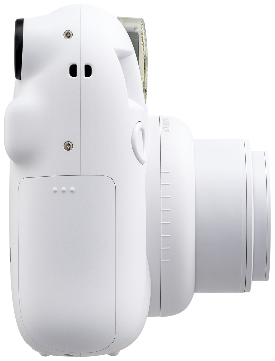 Eine schräge Dreiviertelansicht der weißen Fujifilm Instax Mini 12 Sofortbildkamera vor weißem Hintergrund mit direktem Blick auf das ausgedrehte Objektiv mit der Aufschrift „INSTAX LENS 60mm“, den integrierten vertikalen Blitz, den kleinen Selfie-Spiegel