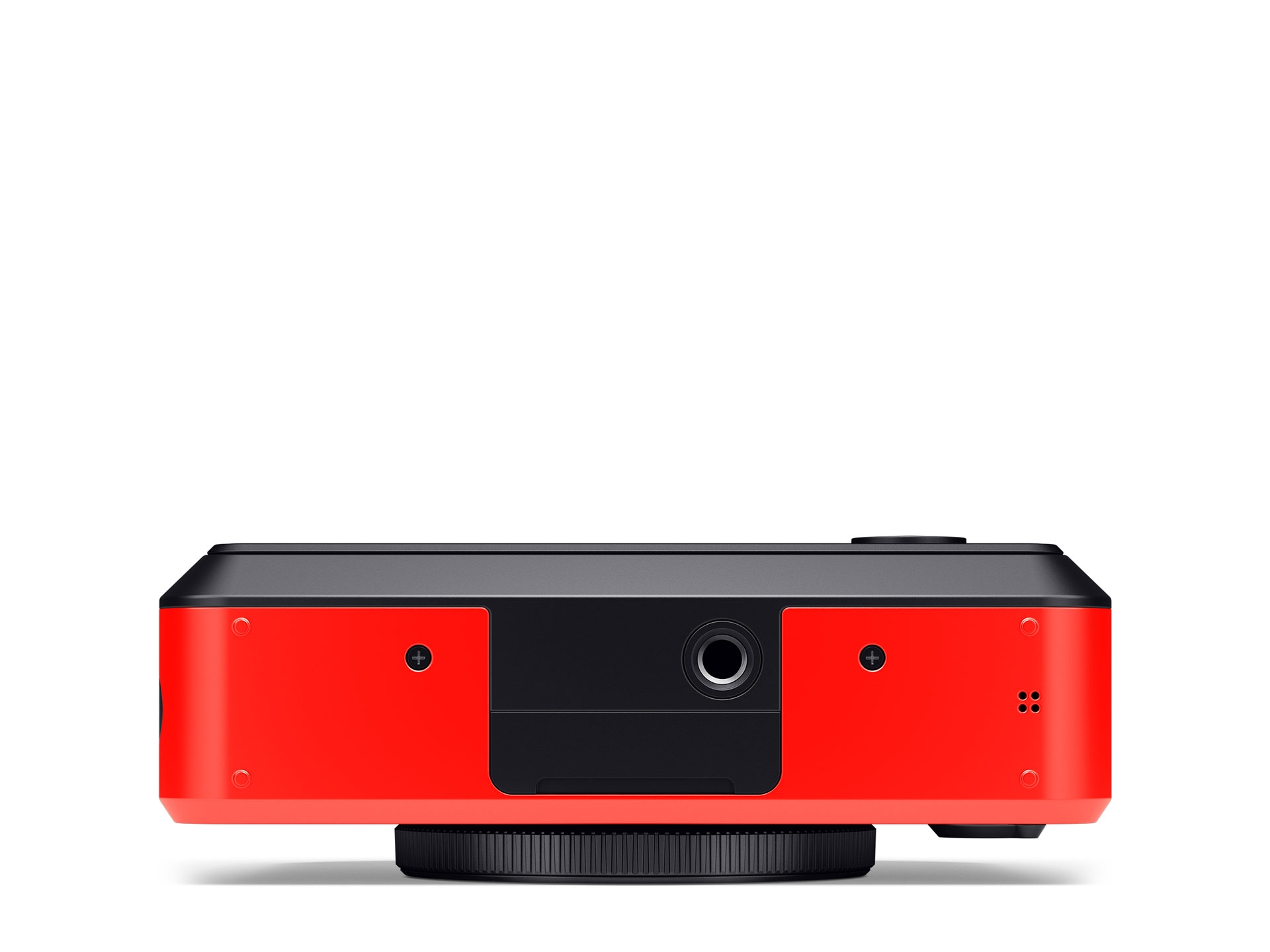 Die Unterseite einer roten Leica Sofort 2 Hybrid-Sofortbildkamera vor einem rein weißen Hintergrund. Das Gehäuse ist zweifarbig in hellem Rot und Schwarz gestaltet, wobei sich im mittleren, schwarzen Bereich ein rundes, metallisches Stativgewinde befindet