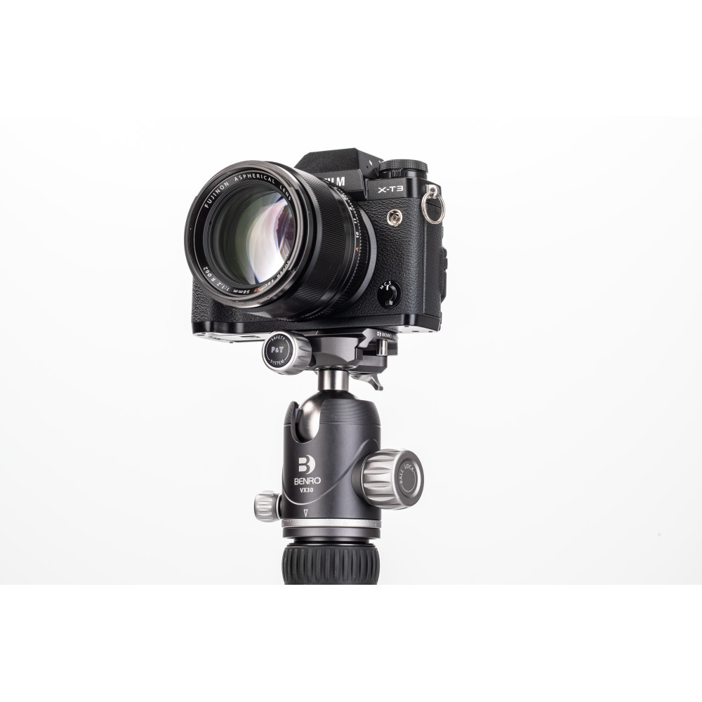Schräge Frontansicht einer schwarzen Fujifilm X-T3 Systemkamera vor weißem Hintergrund mit montiertem Festbrennweiten-Objektiv, befestigt auf einem dunkelgrauen Benro VX25 Stativ-Kugelkopf samt Arca-Swiss-Schnellwechselbasis.