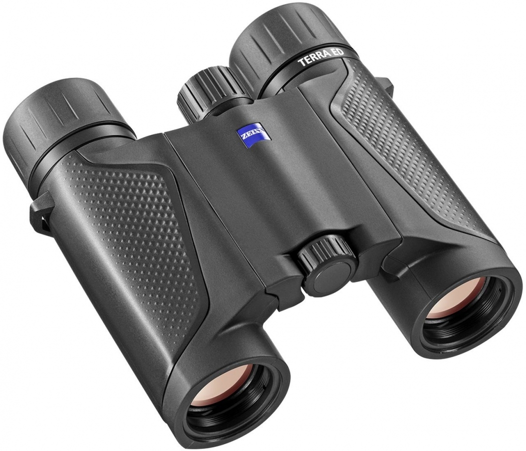 Ein kompaktes, faltbares ZEISS Terra ED Pocket Taschenfernglas in mattem Schwarz, schräg von oben vor einem rein weißen Hintergrund fotografiert. Das Gehäuse verfügt über eine Doppelgelenk-Konstruktion, wobei die seitlichen Griffflächen an den Tuben mit e