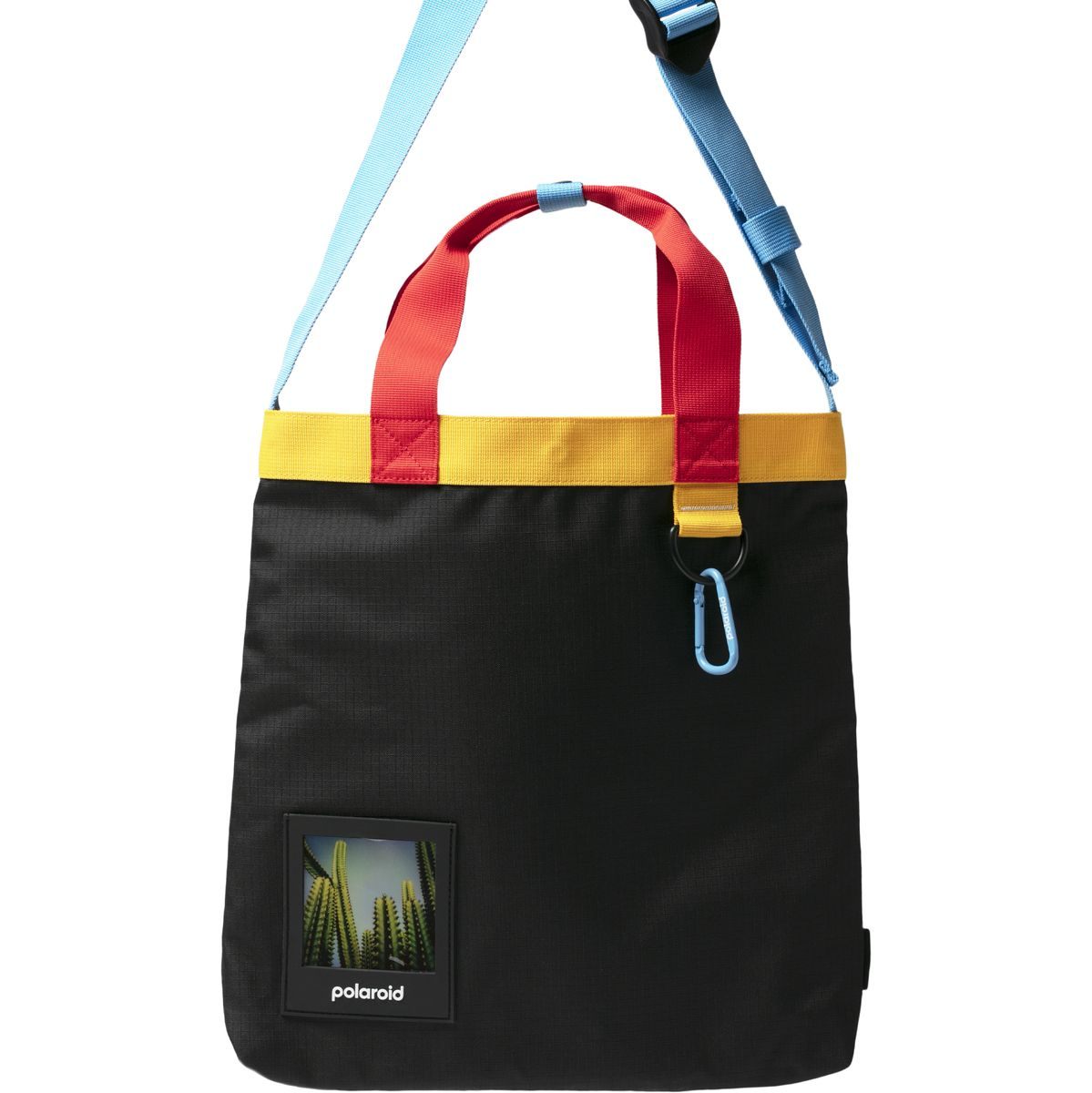 Eine schwarze Polaroid Ripstop Tote Bag vor weißem Hintergrund, gestaltet in den typischen Polaroid-Farben mit roten Henkeln, einem gelben Randstreifen, einem hellblauen Schultergurt mit passendem Karabinerhaken und einem transparenten Fotofach auf der Vo