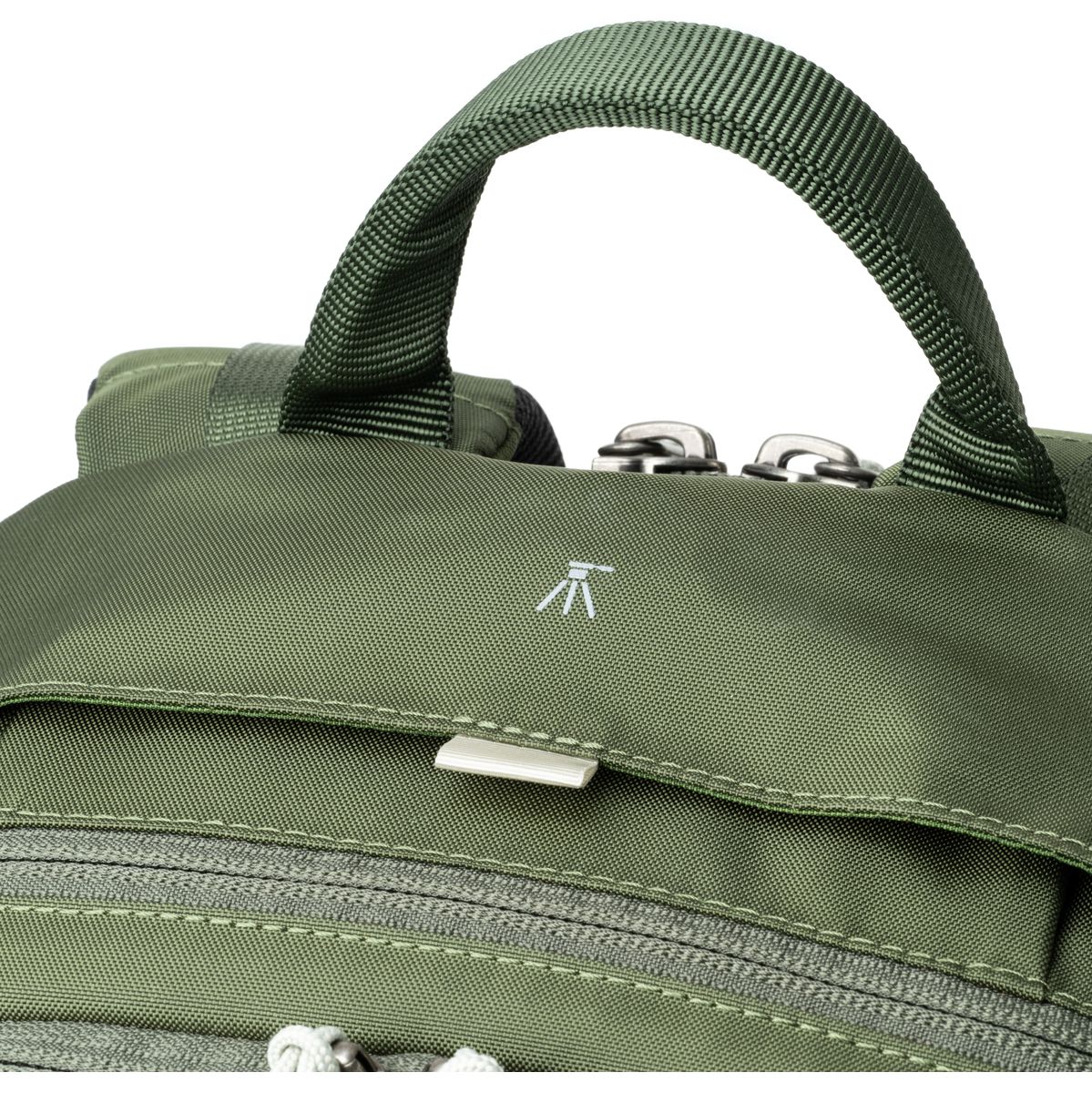 Detailansicht eines grünen Kamerarucksacks mit gepolstertem Tragegriff, Reißverschluss und kleiner Stativ-Markierung.