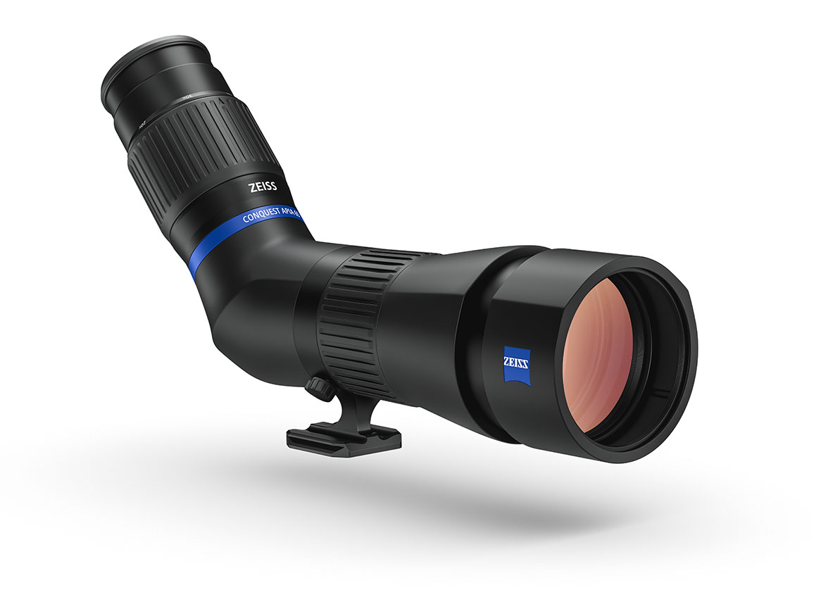 Ein komplett montiertes, schwarzes ZEISS Conquest Gavia 85 Spektiv mit Schrägeinblick, schräg von vorne fotografiert vor einem weißen Hintergrund mit weichem Schattenwurf. Die große Frontlinse im Vordergrund weist eine rötlich-orangefarbene Antireflexbesc