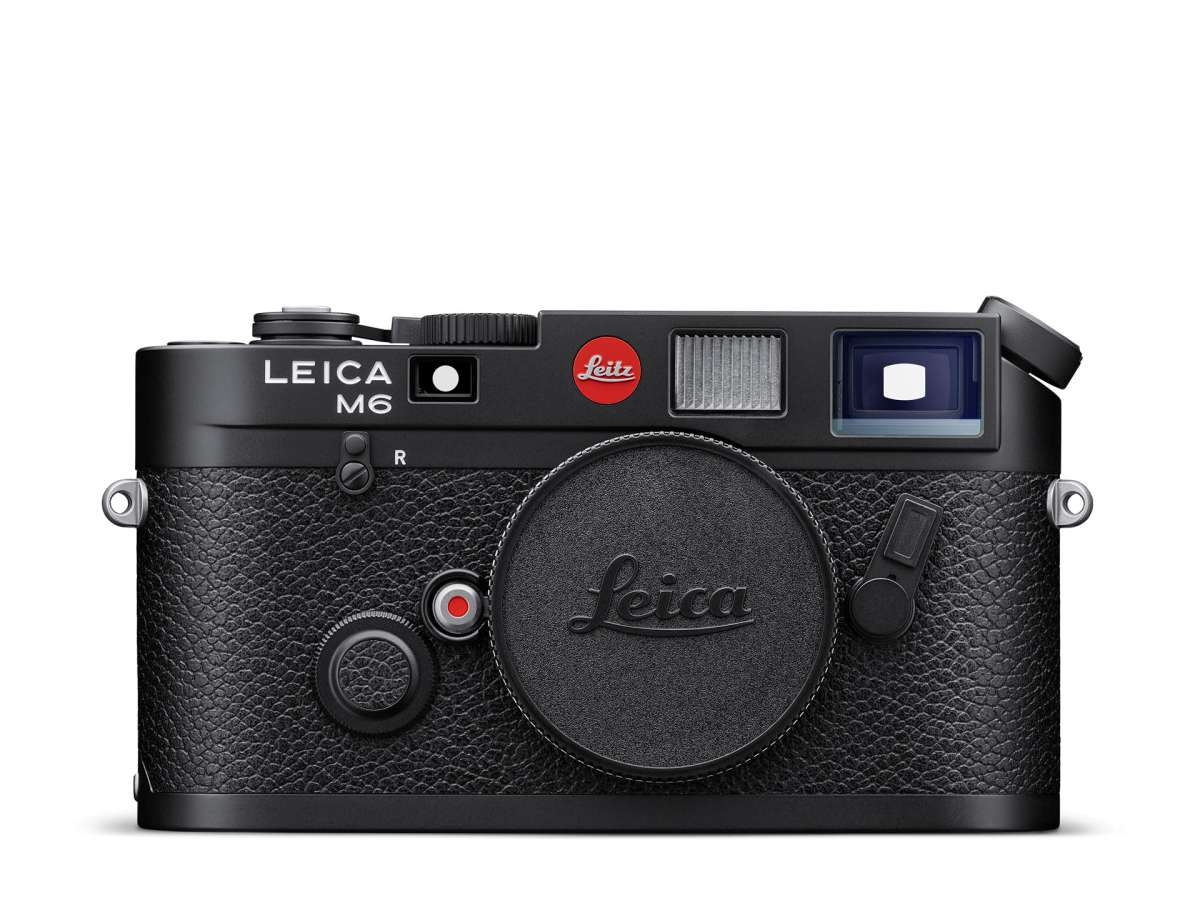 Die frontale Vorderansicht der klassischen, mattschwarzen Leica M6 Messsucherkamera vor weißem Hintergrund mit montiertem Gehäusedeckel inklusive Leica-Schriftzug, dem markanten roten Leitz-Logo-Punkt in der Mitte und der weißen Gravur „LEICA M6“ auf der
