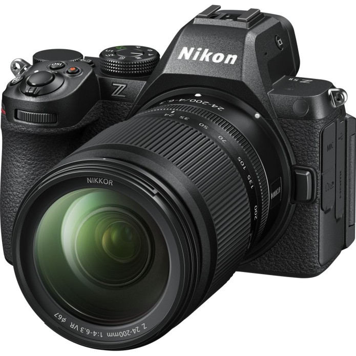 Schräge Frontansicht einer schwarzen Nikon Z5 Vollformat-Systemkamera vor weißem Hintergrund mit montiertem NIKKOR Z 24-200mm f/4-6.3 VR Superzoom-Objektiv, sichtbarem Nikon-Markenlogo auf dem Sucherhügel sowie weißer Brennweitenskala am ausladenden Objek