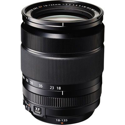 Ein schwarzes Fujifilm XF 18-135mm f/3.5-5.6 R LM OIS WR Allround-Zoomobjektiv stehend in der Vorderansicht auf weißem Hintergrund mit gut sichtbaren Brennweitenmarkierungen, Fokus- und Zoomring sowie der „XF ZOOM“-Plakette am unteren Gehäuserand.