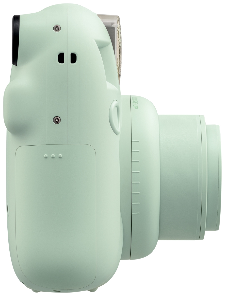 Fujifilm Instax Mini 12 Sofortbildkamera vor weißem Hintergrund mit direktem Blick auf das ausgedrehte Objektiv mit der Aufschrift „INSTAX LENS 60mm“, den integrierten vertikalen Blitz, den kleinen Selfie-Spiegel neben der Linse und den dezenten Produktau