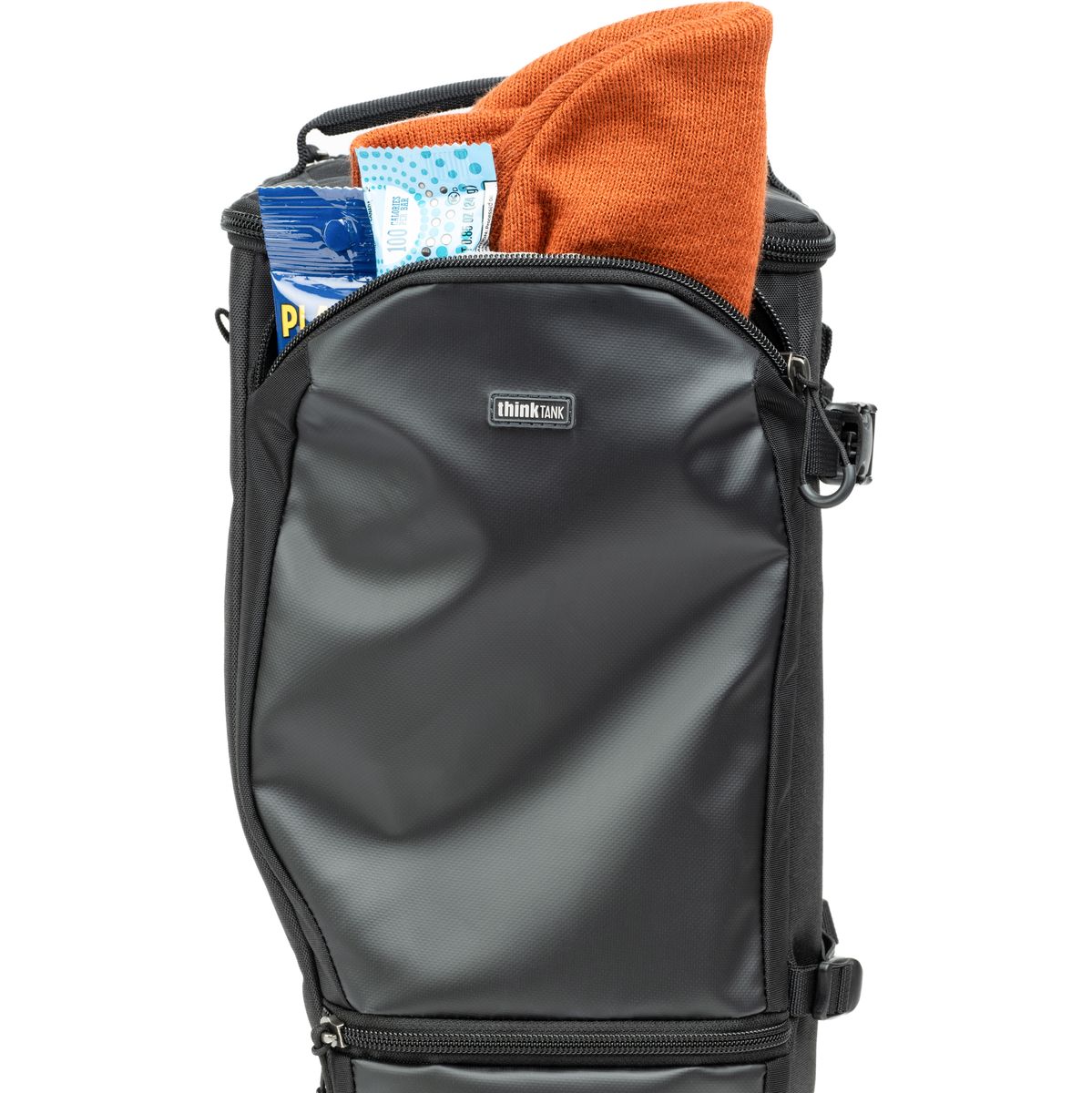Schwarzes Kamera-Holster mit geöffnetem oberen Fach, in dem ein orangefarbenes Tuch und weiteres Zubehör verstaut sind.