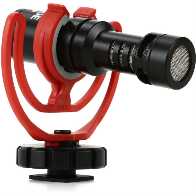 Perspektivische Frontansicht des kompakten Rode VideoMicro Richtmikrofons, eingespannt in der roten Rycote Lyre Schockabsorber-Halterung mit Blitzschuh-Adapter vor weißem Hintergrund.