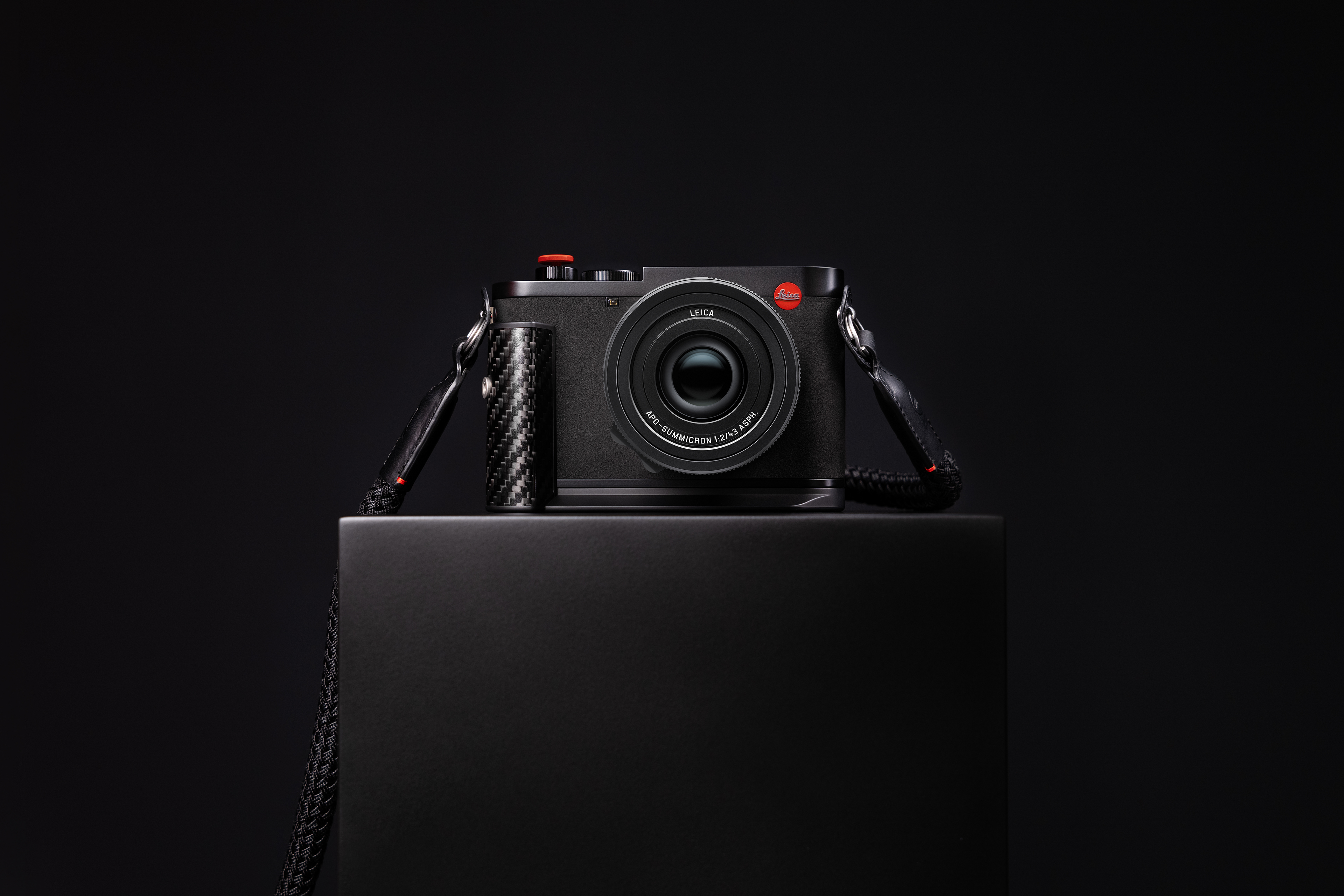 Leica Q3 43 F1 Sonderedition mit APO-Summicron Objektiv auf einem schwarzen Podest vor dunklem Hintergrund.