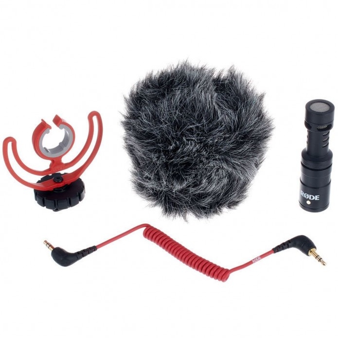 Der Lieferumfang des Røde VideoMicro On-Camera-Richtmikrofons auf weißem Hintergrund, bestehend aus dem ultrakompakten schwarzen Mikrofongehäuse, der roten Rycote Lyre Schwinghalterung, dem markanten, fellartigen WS9-Windschutz (Deadcat) und einem roten 3