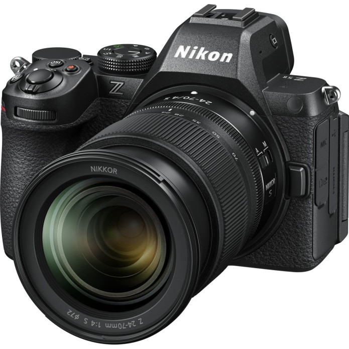 Schräge Frontansicht einer schwarzen Nikon Z5 II Systemkamera vor weißem Hintergrund mit montiertem NIKKOR Z 24-70mm f/4 S High-Performance-Zoom-Objektiv, gut sichtbarem Nikon-Markenlogo auf dem Sucherhügel sowie weißer Typenprägung am Objektivrand.