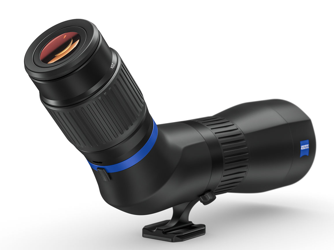 Ein schwarzes ZEISS Conquest Gavia 85 Spektiv mit Schrägeinblick, schräg von hinten fotografiert vor einem weißen Hintergrund mit weichem Schattenwurf. Das Okular im linken Vordergrund zeigt eine rötlich-orangefarbene Antireflexbeschichtung auf der Linse.