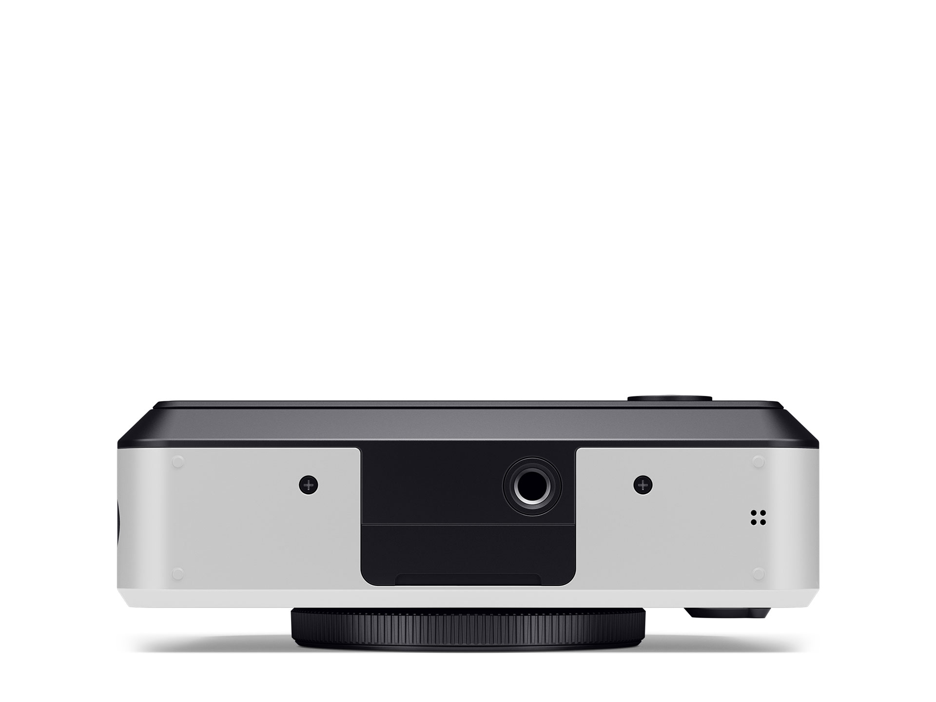 Die Unterseite einer hybriden, weiß-schwarzen Leica SOFORT 2 Sofortbildkamera, freigestellt auf weißem Hintergrund. Die weiße Gehäusebasis zeigt ein zentrales, schwarzes Element, in das das standardisierte Stativgewinde eingelassen ist. Links und rechts d