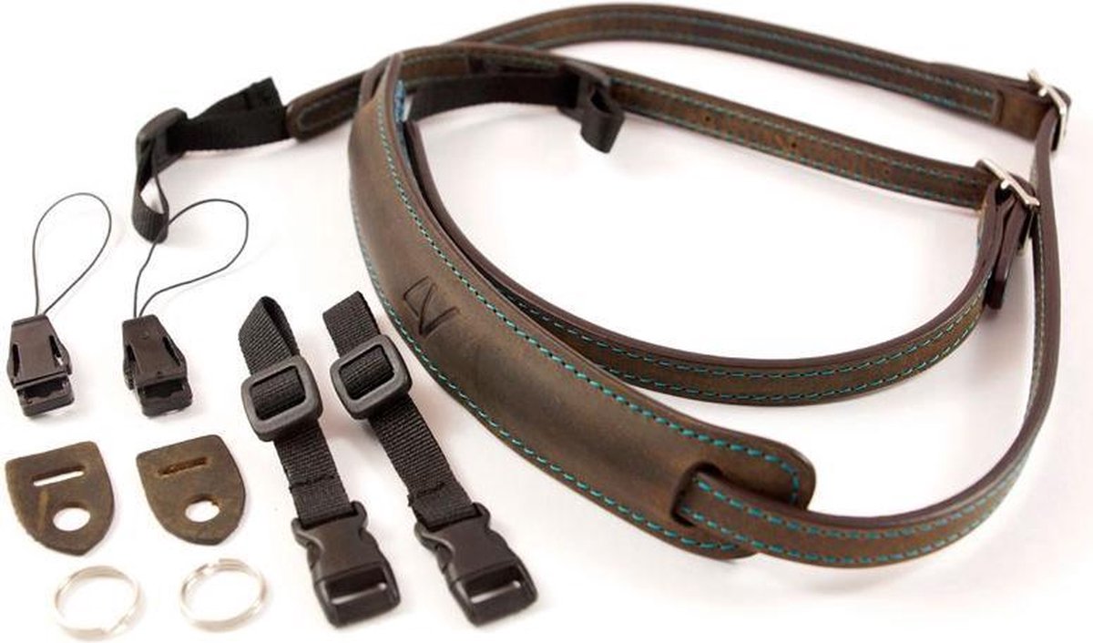Draufsicht des 4V Design Lusso Kamera-Schultergurts aus gewaschenem Tuscany-Leder in Grün-Braun mit Ziernähten sowie dem im Lieferumfang enthaltenen Universal-Fit-Zubehörkit bestehend aus Adaptern, Riemen und Splintringen vor weißem Hintergrund.