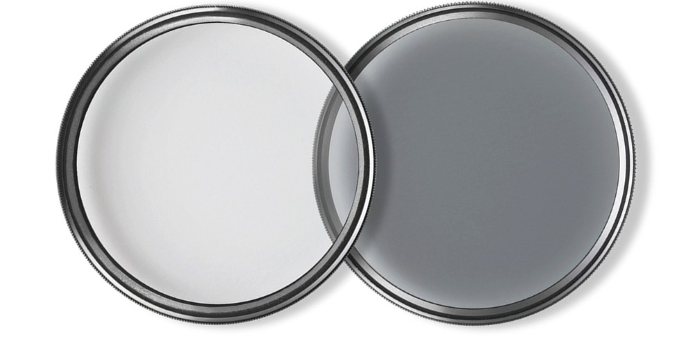 Zwei kreisrunde Kamerafilter von ZEISS, ein glasklarer T* UV-Filter (links) und ein grau getönter, zirkularer T* POL-Filter (rechts), die sich in der Bildmitte leicht überlappen, freigestellt vor einem rein weißen Hintergrund. Beide Filter besitzen eine f