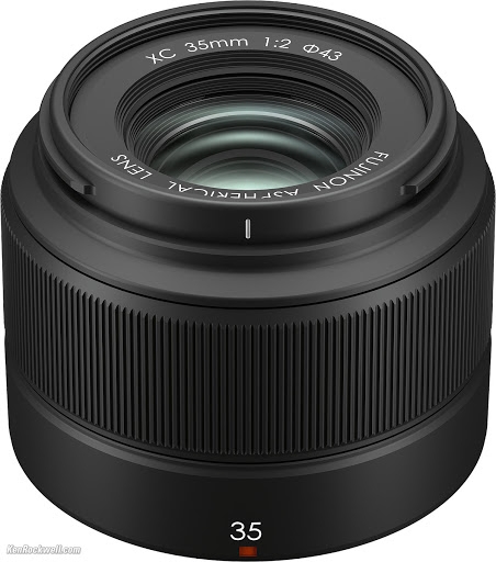 Schrägansicht von oben auf ein kompaktes, schwarzes Fujifilm XC 35mm f/2 Objektiv (Fujinon X-Mount Festbrennweite) mit Blick auf den breiten, geriffelten Fokusring sowie den beschrifteten Frontring mit den Angaben „XC 35mm 1:2 ⌀43“ und „FUJINON ASPHERICAL